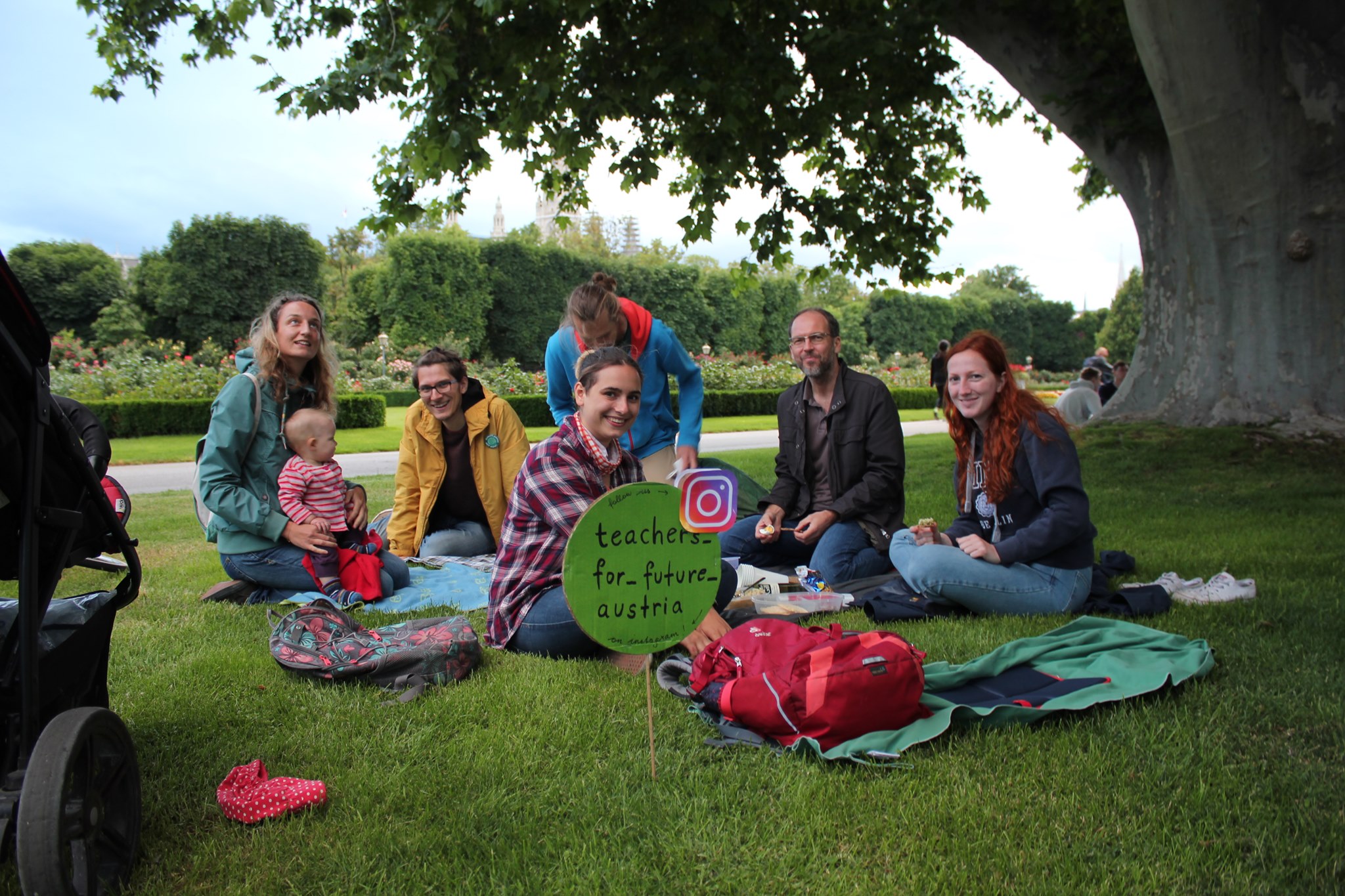 Teachers For Future sitzen auf einer Wiese mit Instagram-Tag Schild „teachers_for_future_austria"